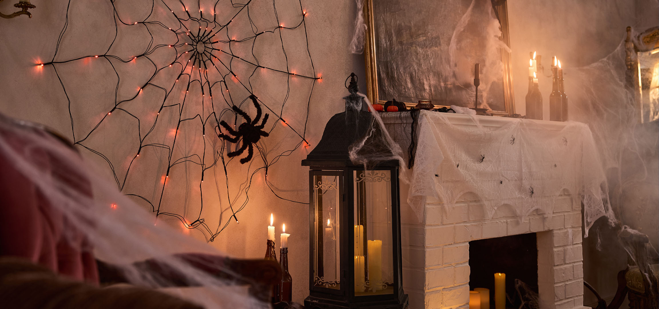 Halloween-Dekorationen mit Spinnennetzlichtern, einer großen Spinne und Kerzen.