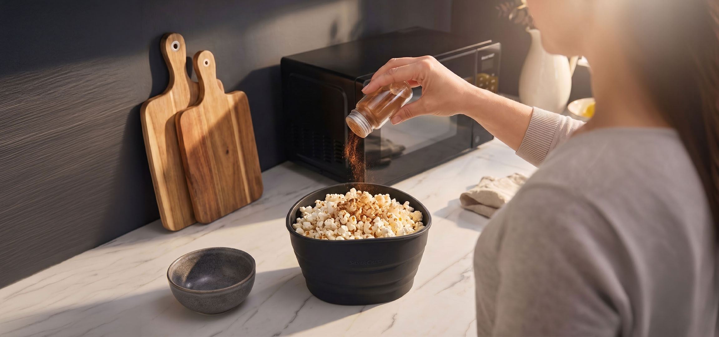 AI-generiert: Popcorn in einer schwarzen Schüssel, gewürzt mit Gewürzen, neben Holzschneidebrettern.
