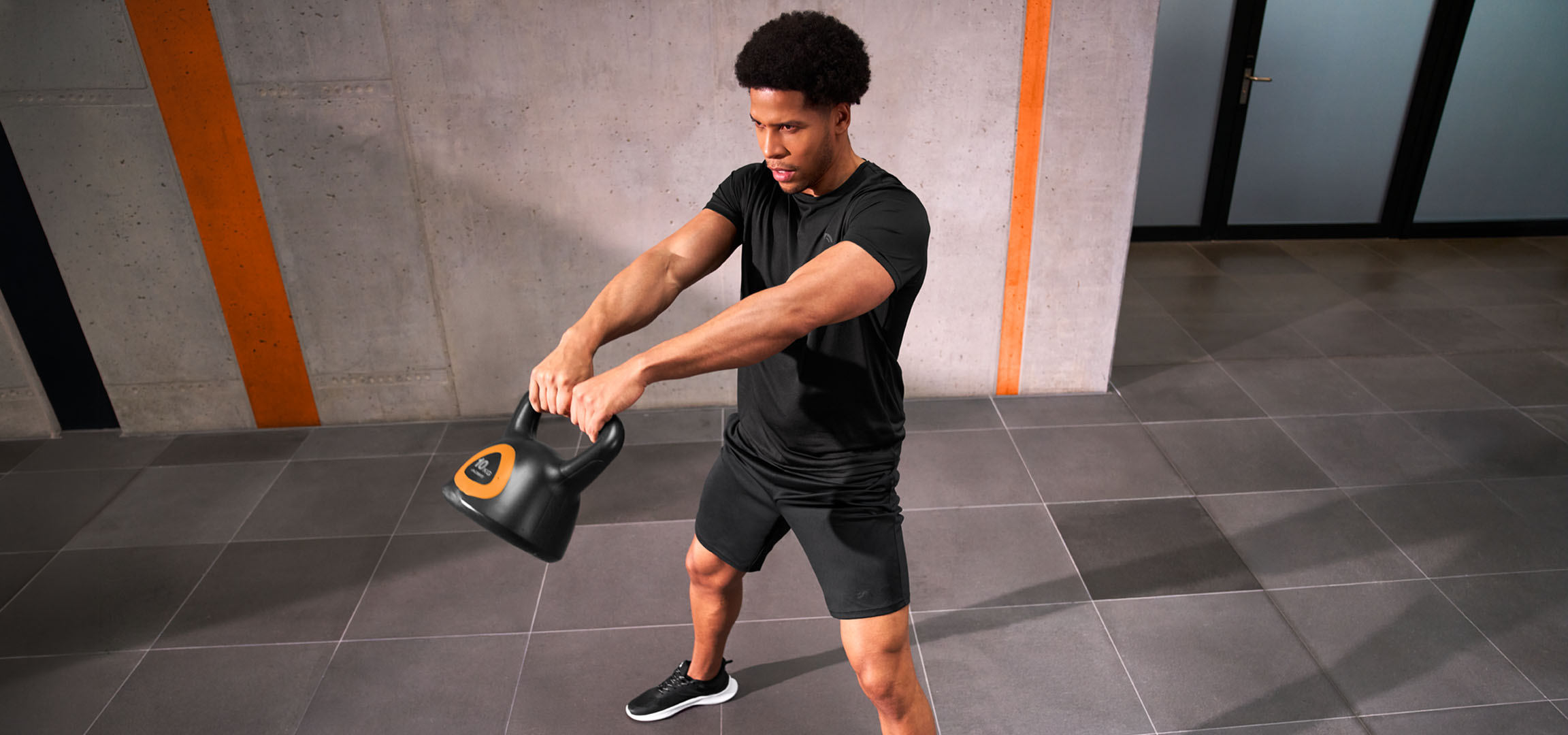 AI-generiert: Mann trainiert mit einer schwarz-orangen Kettlebell.