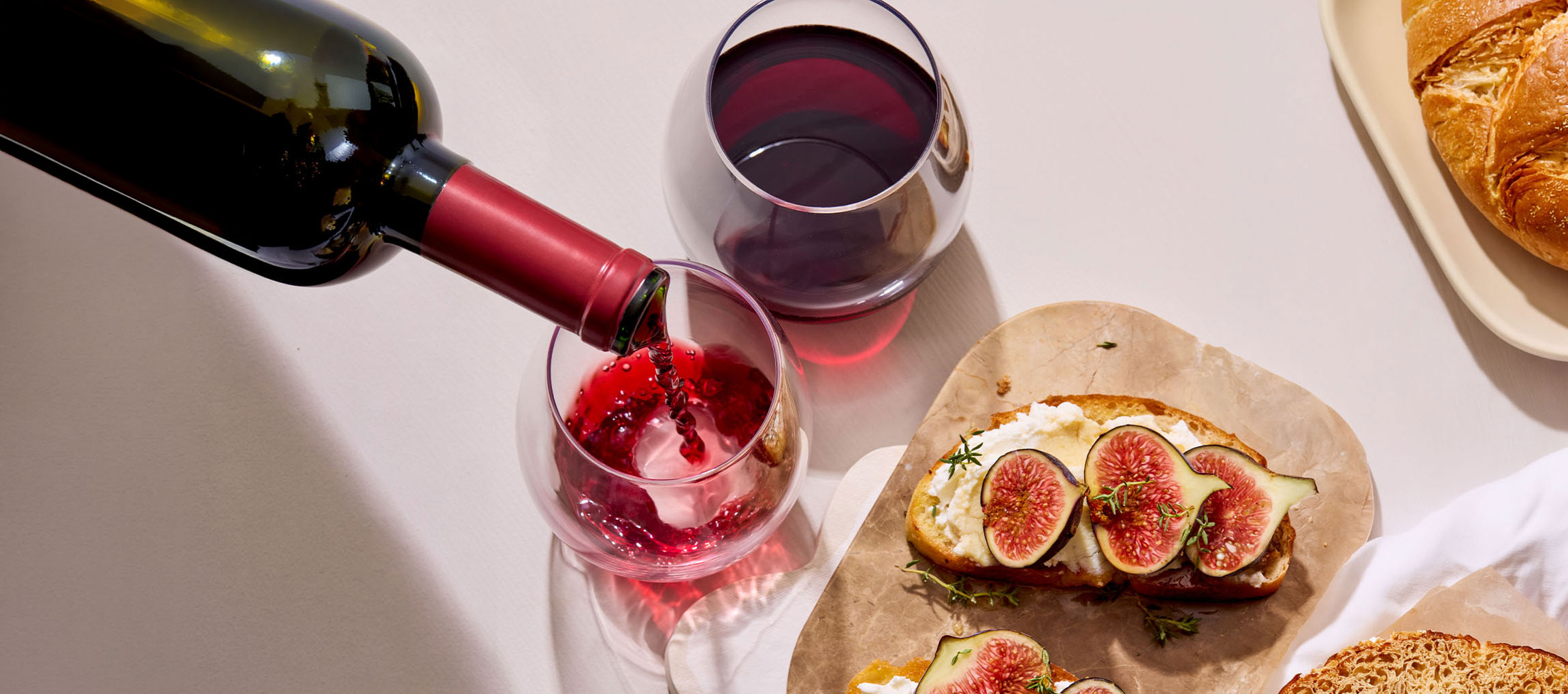 Rotwein wird in ein Glas gegossen, dazu Feigen- und Käse-Bruschetta.