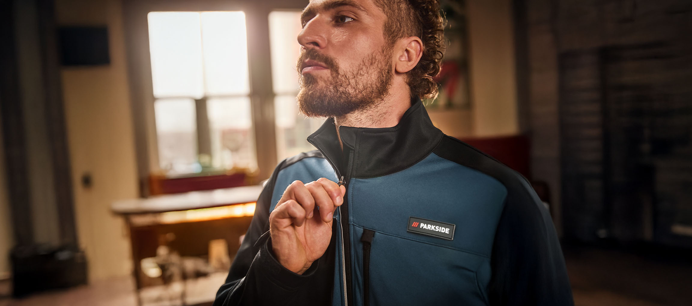 Mann in einer blau-schwarzen Parkside Arbeitsjacke, die er zuzieht