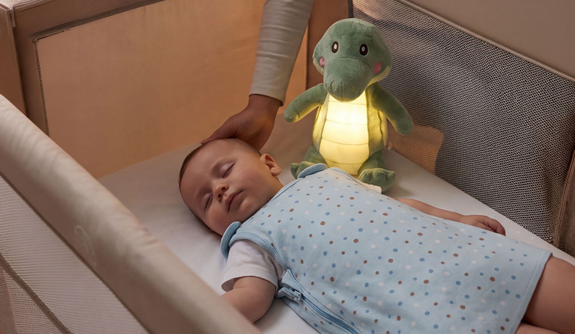 Baby schläft im Kinderbett mit Kuscheltier und Elternhand.