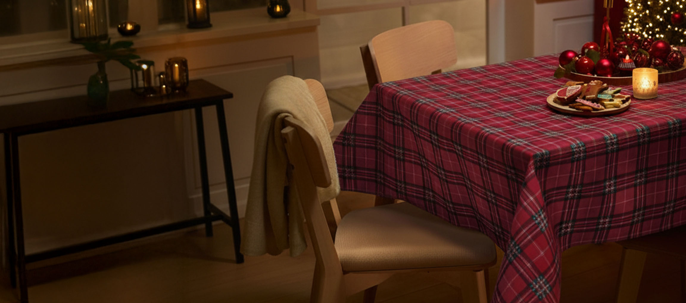 Weihnachtlich gedeckter Tisch mit rot karierter Tischdecke, Stühlen und Weihnachtsplätzchen.