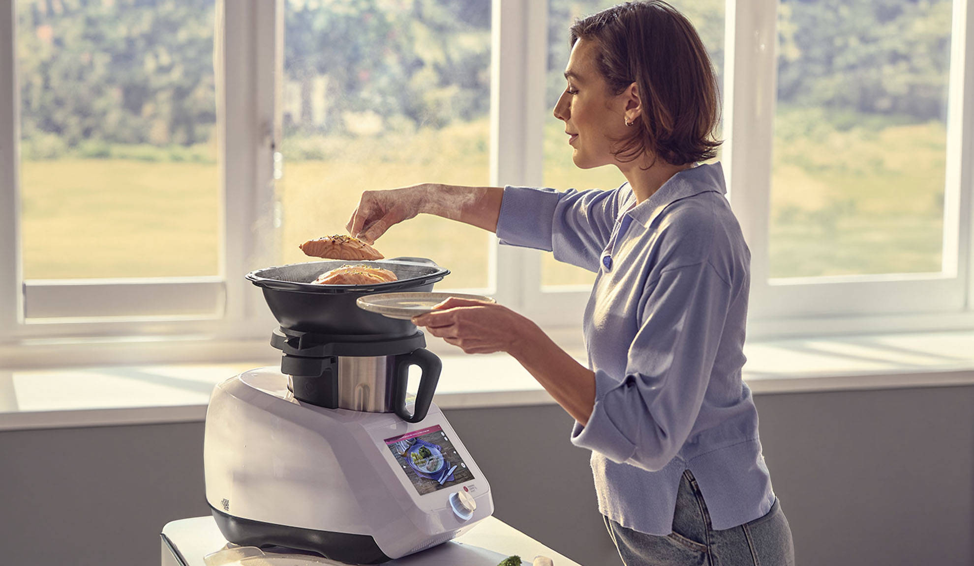 Frau kocht Lachs in einer Küchenmaschine mit Dampffunktion, über den digitalen Bildschirm.