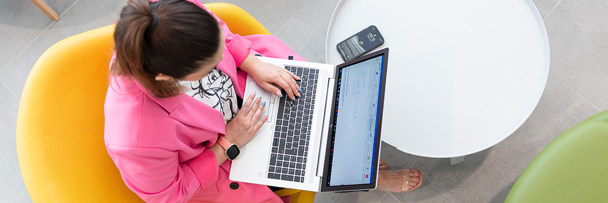 Frau arbeitet an Laptop und Handy.