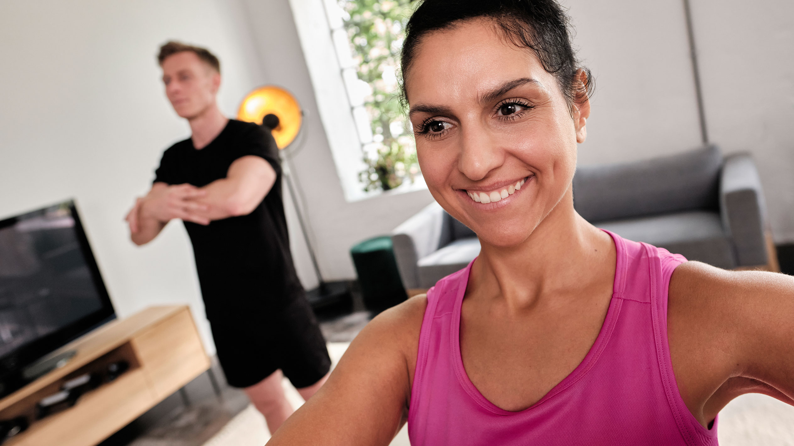 Lächelnde Frau, die zu Hause mit ihrem Partner trainiert.