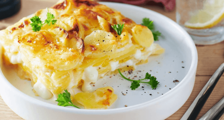 Kartoffelgratin mit Käse und Petersilie auf einem weißen Teller